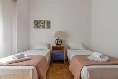 a room with three beds and a table with a lamp at Nice 2bedroom apartment in Pagkrati in Athens