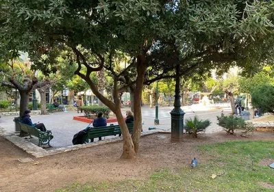people sitting on benches under a tree in a park at Sunny Apartment (90m2) in Athens center in Athens