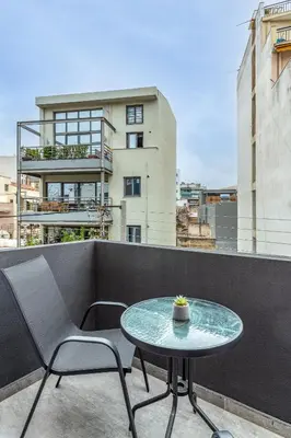 a table and chairs on a balcony with a building at Athena Studio in Gazi in Athens