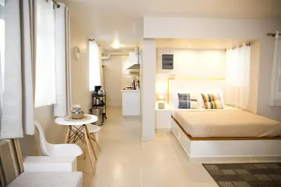 a white bedroom with a bed and a small table at Praxitelis Luxury Apartments in Athens