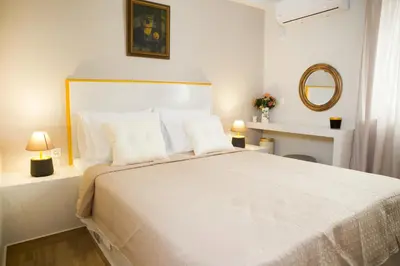 a white bedroom with a large bed with white pillows at Praxitelis Luxury Apartments in Athens