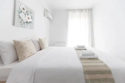 a white bedroom with a large white bed with pillows at Stylish spacious apartment in Palaio Faliro (C1) in Athens