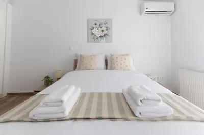 a white bedroom with a white bed with towels on it at Stylish spacious apartment in Palaio Faliro (C1) in Athens