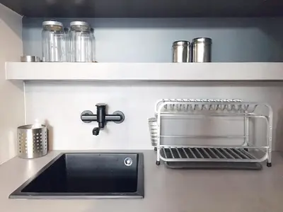 a kitchen counter with a sink and a drying rack at Susanna Apartments - Your Oasis in Athens Ano Petralona in Athens