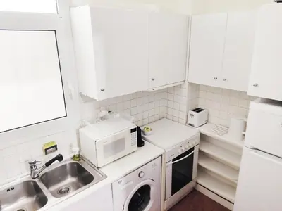 a white kitchen with a sink and a microwave at Under the Rock of Acropolis by YHA in Athens