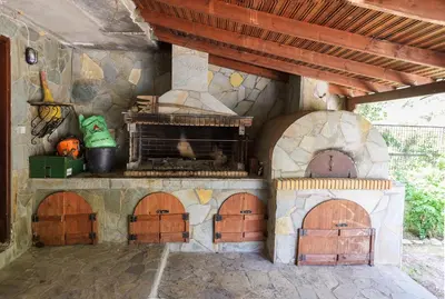 an outdoor kitchen with an outdoor oven with wood doors at Marin Holiday in Dhaskalión