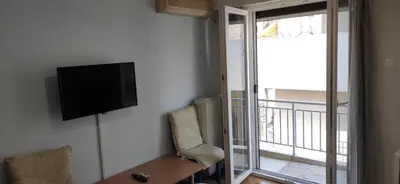 a living room with a television and a table and chairs at JiMMYS STUDIO, KALIMARMARO in Athens