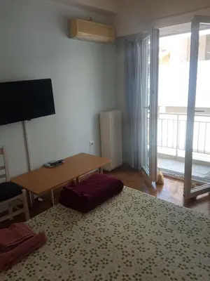a living room with a table and a desk and a television at JiMMYS STUDIO, KALIMARMARO in Athens