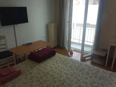 a bedroom with a bed and a table and a television at JiMMYS STUDIO, KALIMARMARO in Athens
