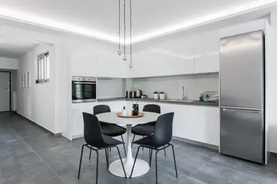 a white kitchen with a table and chairs at Stellar 3BR Apartment with Balcony by UPSTREET in Athens