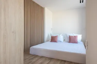 a bedroom with a bed with white sheets and pink pillows at Ceramian Athens in Athens