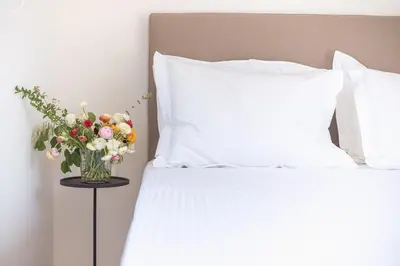 a vase of flowers on a table next to a bed at Ceramian Athens in Athens
