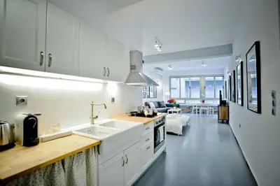 a white kitchen with a sink and a living room at The old Tailor Factory White Room in Athens