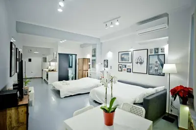a bedroom with two beds and a table and a couch at The old Tailor Factory White Room in Athens