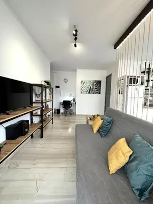 a living room with a couch and a television at Zeus Bright & New Apartment - 25' walk to the Acropolis in Athens