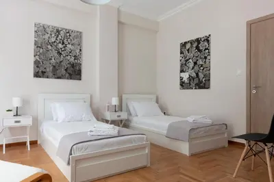 two beds in a room with white walls at Spacious Central Flat in the heart of Athens! in Athens