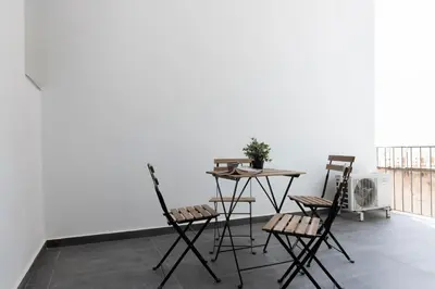a table and chairs in a room with a white wall at Spacious Central Flat in the heart of Athens! in Athens