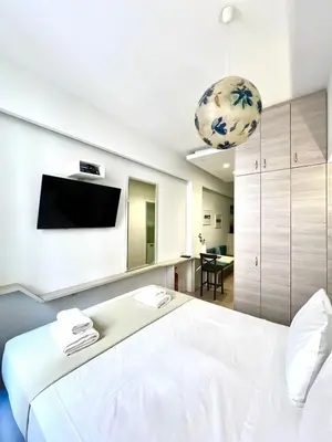 a bedroom with a white bed and a flat screen tv at Monastiraki 106 SuperHost Hub in Athens