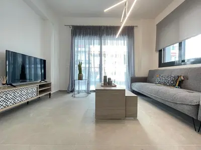 a living room with a couch and a flat screen tv at Athenean Modern Escape near Marina Flisvos in Athens