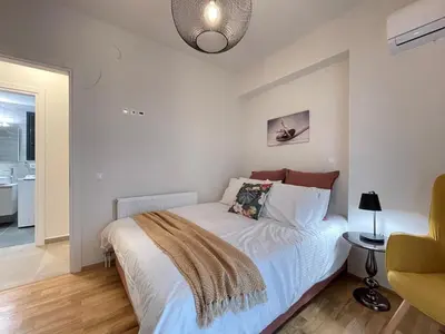 a bedroom with a bed with white sheets and a lamp at Athenean Modern Escape near Marina Flisvos in Athens