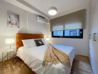 a bedroom with a bed with white sheets and a window at Athenean Modern Escape near Marina Flisvos in Athens
