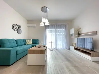 a living room with a blue couch and a tv at Athenean Modern Escape near Marina Flisvos in Athens