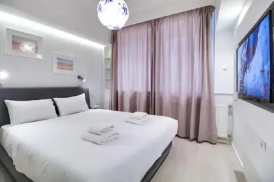 a bedroom with a large white bed and a flat screen tv at Monastiraki 107 SuperHost Hub in Athens