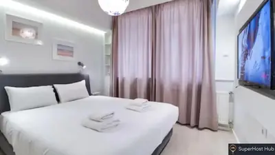 a bedroom with a white bed and a flat screen tv at Monastiraki 107 SuperHost Hub in Athens