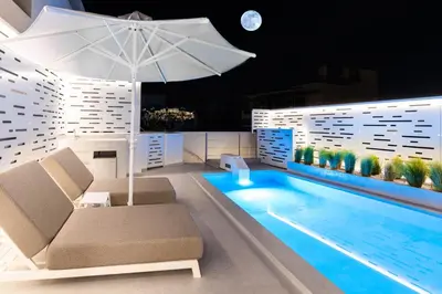 a pool with a chair and an umbrella next to it at Ma Maison No5, Private Heated Pool, Acropolis view in Athens