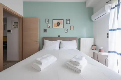 a bedroom with a white bed with two towels on it at Confy Living Apartment Metaxourghio Metro Station in Athens