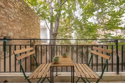 two wooden chairs and a table on a balcony at Confy Living Apartment Metaxourghio Metro Station in Athens