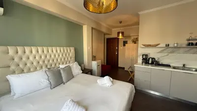 a bedroom with a large white bed and a kitchen at Monastiraki 509 Central Suite in Athens