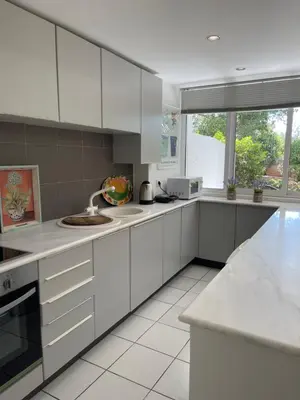 a kitchen with white cabinets and a sink at Vouliagmeni‘s Secret Garden near the Sea in Athens
