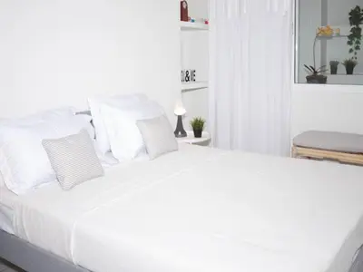 a white bed with white pillows in a bedroom at Vouliagmeni‘s Secret Garden near the Sea in Athens