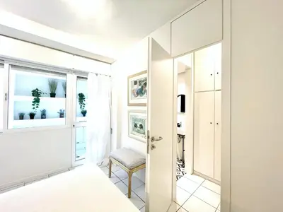 a white bedroom with a mirror and a chair at Vouliagmeni‘s Secret Garden near the Sea in Athens