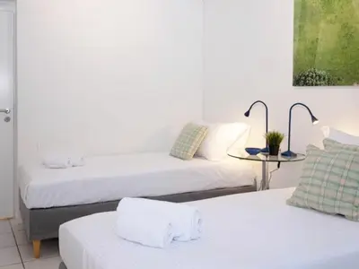 a room with two beds and a table with a tableasteryasteryasteryasteryastery at Vouliagmeni‘s Secret Garden near the Sea in Athens
