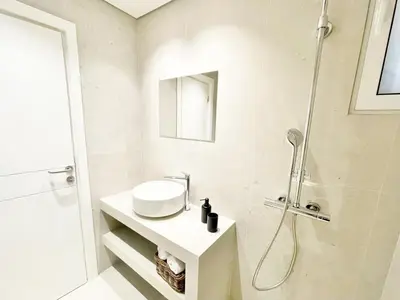 a white bathroom with a shower and a sink at Vouliagmeni‘s Secret Garden near the Sea in Athens