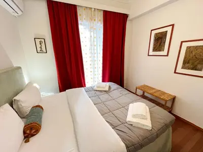 a bedroom with a bed and a window with red curtains at A Stroll to the Acropolis - By Athenian Homes in Athens