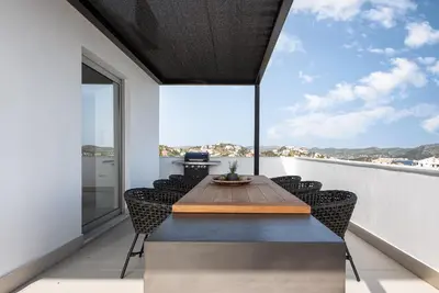 a dining room with a table and chairs on a balcony at Black Stone Villa in Sounio