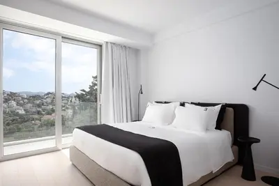 a white bedroom with a bed and a large window at Black Stone Villa in Sounio