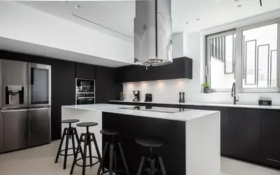 a kitchen with black and white cabinets and bar stools at Black Stone Villa in Sounio