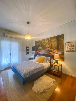 a bedroom with a bed and a painting on the wall at Nina's cozy apartment in Mikrolimano in Piraeus