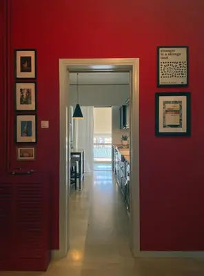 a hallway with a red wall with a door and a dining room at Nina's cozy apartment in Mikrolimano in Piraeus