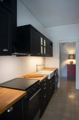 a kitchen with black cabinets and a sink at Nina's cozy apartment in Mikrolimano in Piraeus