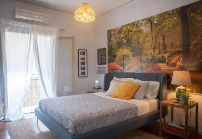 a bedroom with a bed with a painting on the wall at Nina's cozy apartment in Mikrolimano in Piraeus