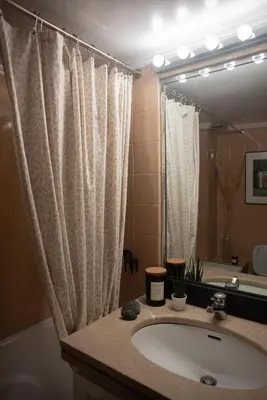 a bathroom with a sink and a tub and a mirror at Nina's cozy apartment in Mikrolimano in Piraeus