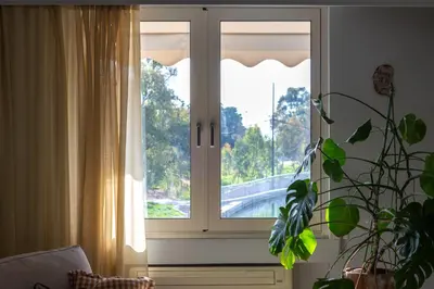 a window with curtains and a plant in a room at Nina's cozy apartment in Mikrolimano in Piraeus