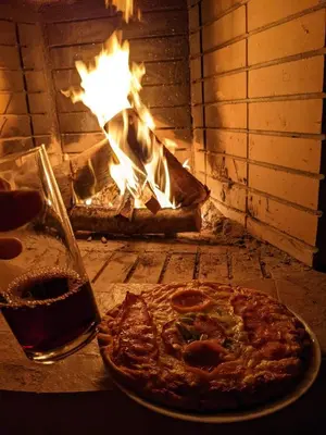 a pizza and a glass of beer next to a brick oven at Little Beach Chalet in Saronida
