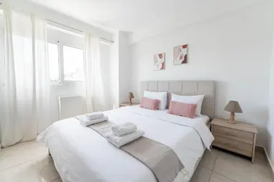 a white bedroom with a large white bed with pink pillows at Modern spacious apartment located in Piraeus (B8) in Piraeus
