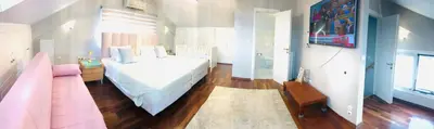 a bedroom with a white bed and a pink couch at Beautiful maisonette with a view to the mountains and the sea in Aghia Marina